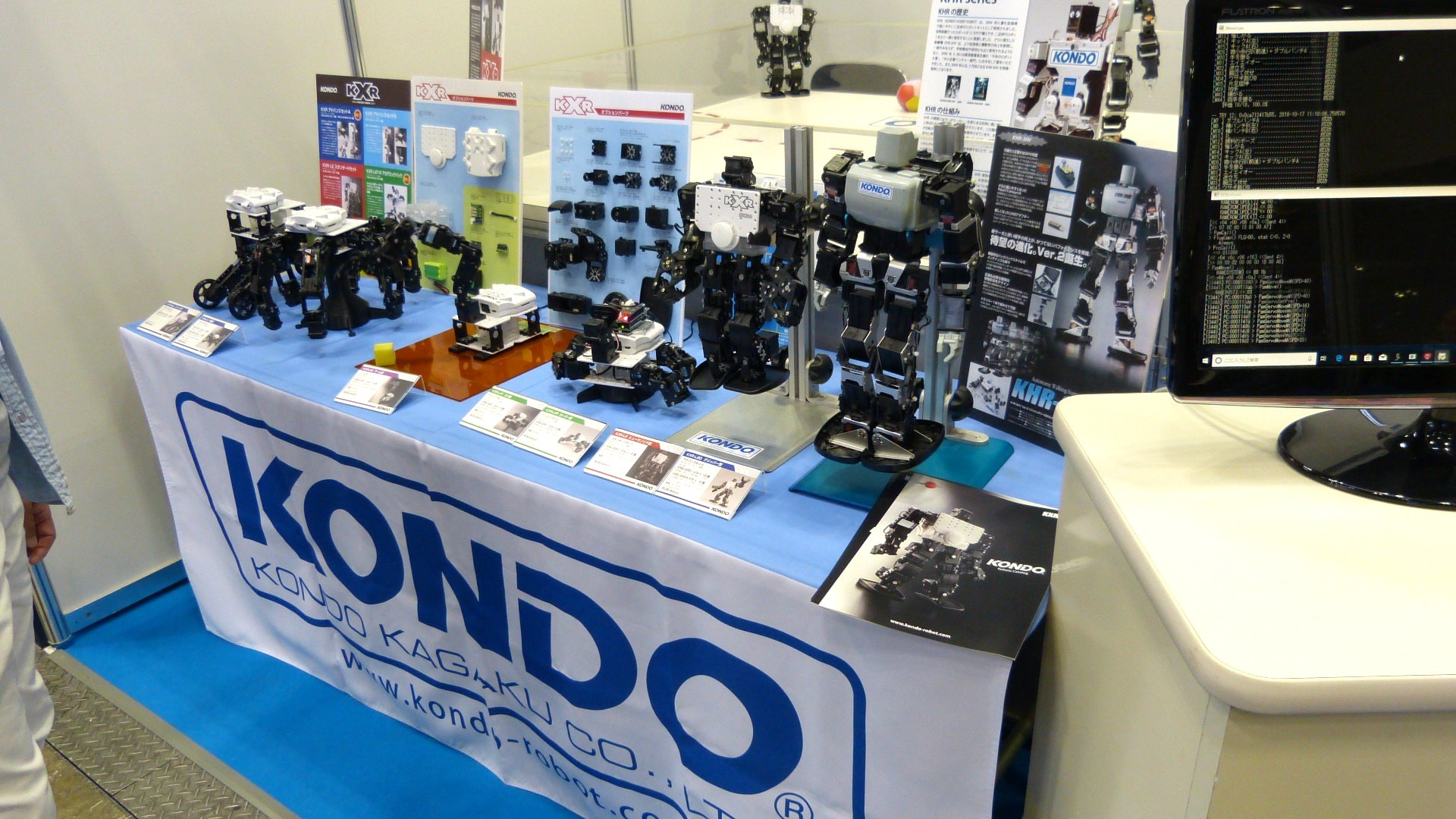 a counter with a Kondo logo banner displaying small robot parts such as arms and legs